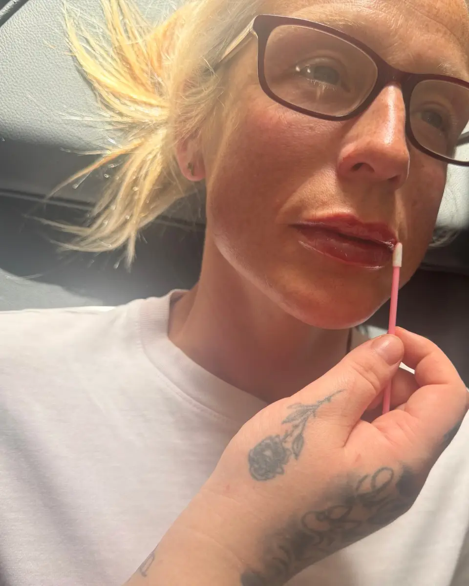 Client with full, glossy lips holding a pink lip applicator